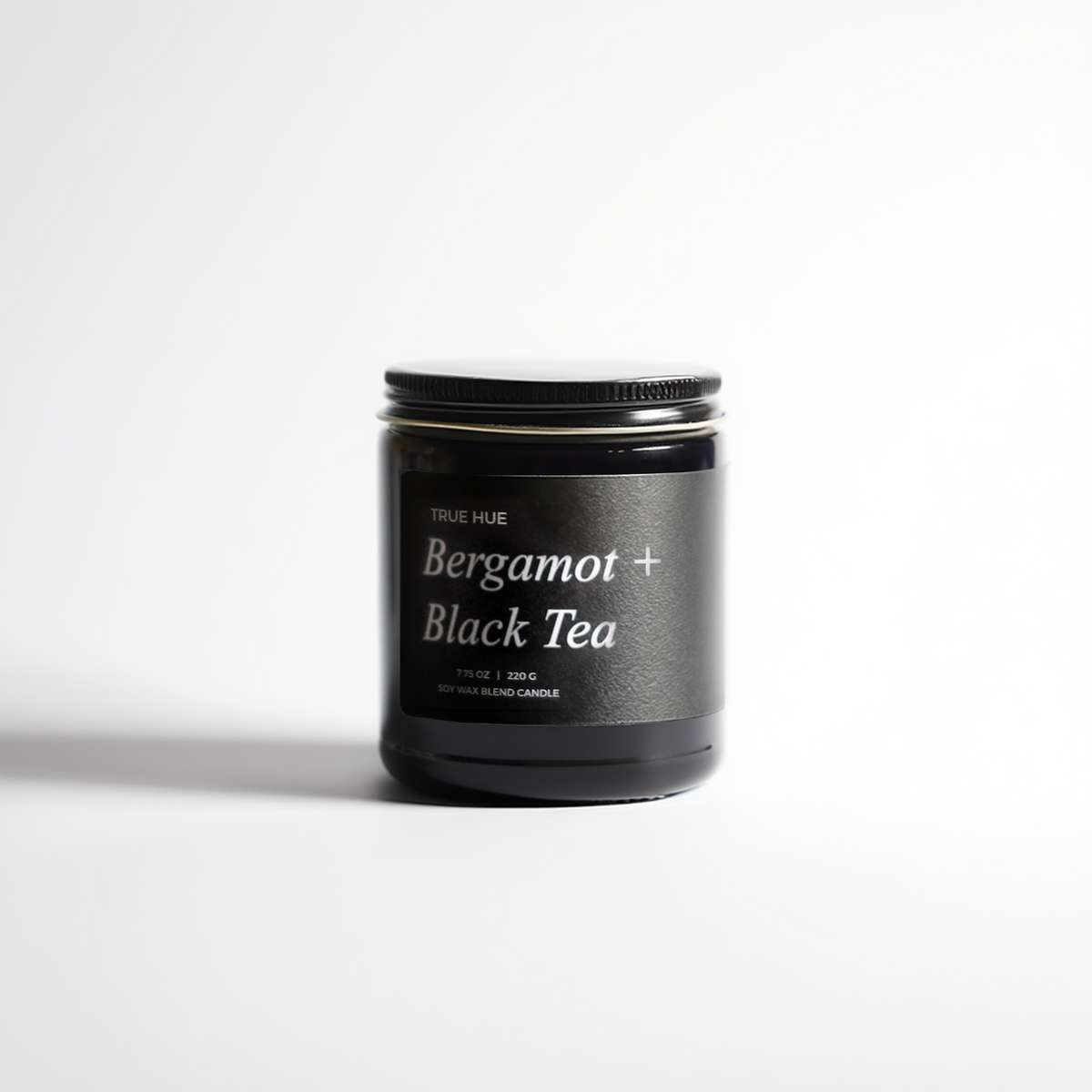 Black candle jar with 'Bergamot + Black Tea' label on a white background