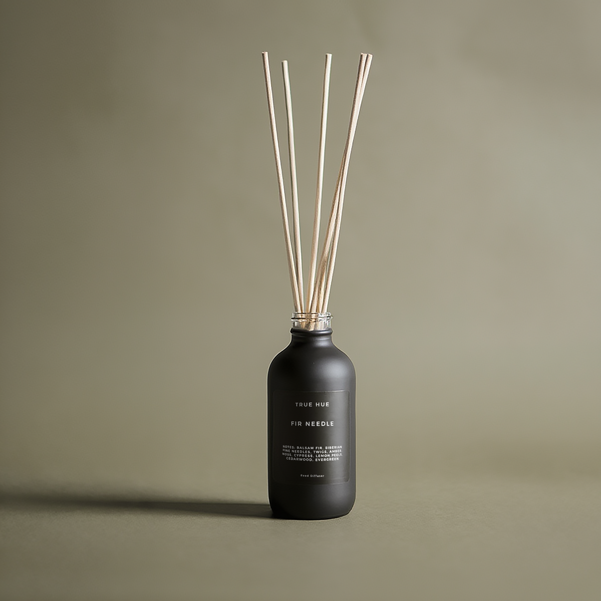 Black diffuser bottle with wooden sticks on a beige background