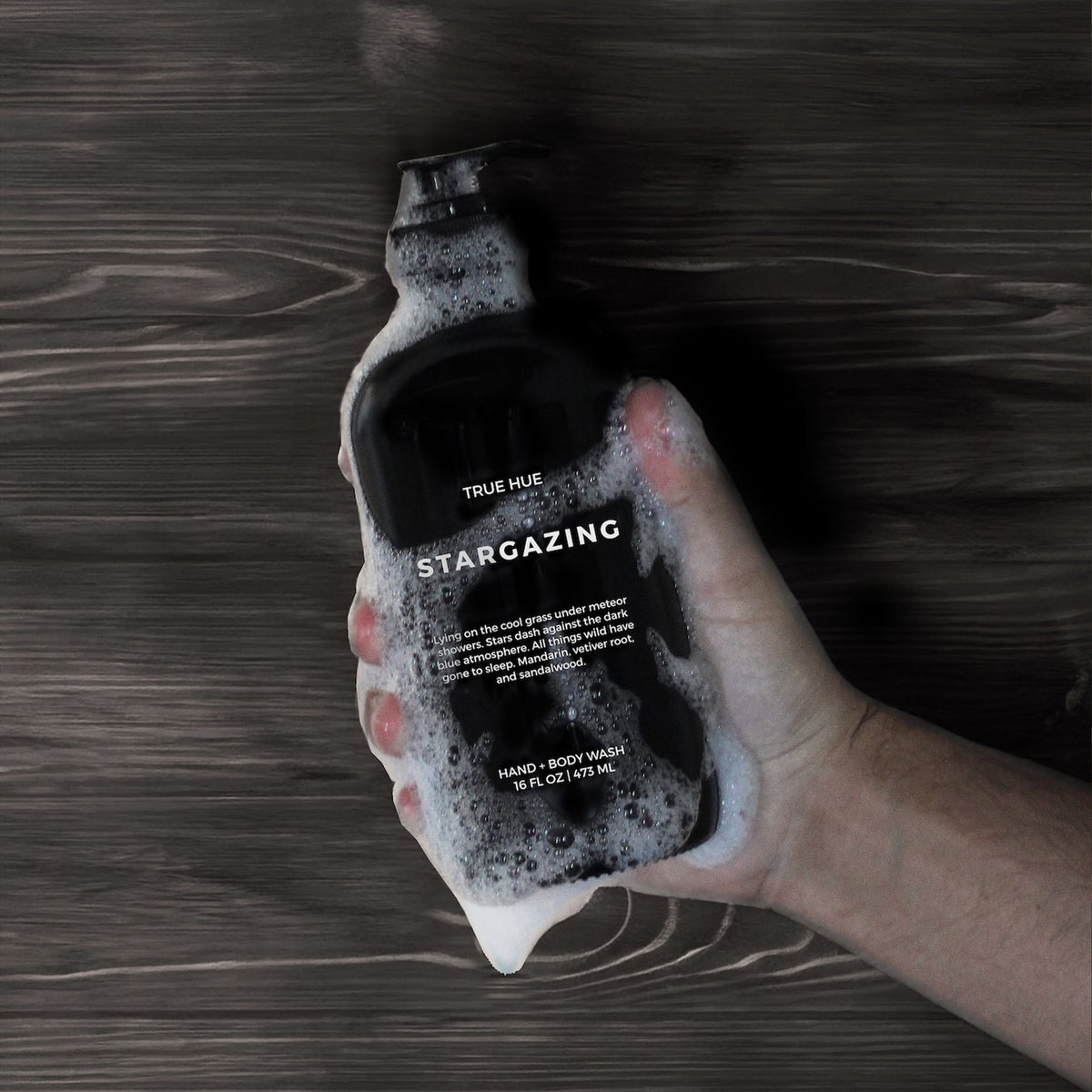 a hand holding a soapy bottle of stargazing hand soap.