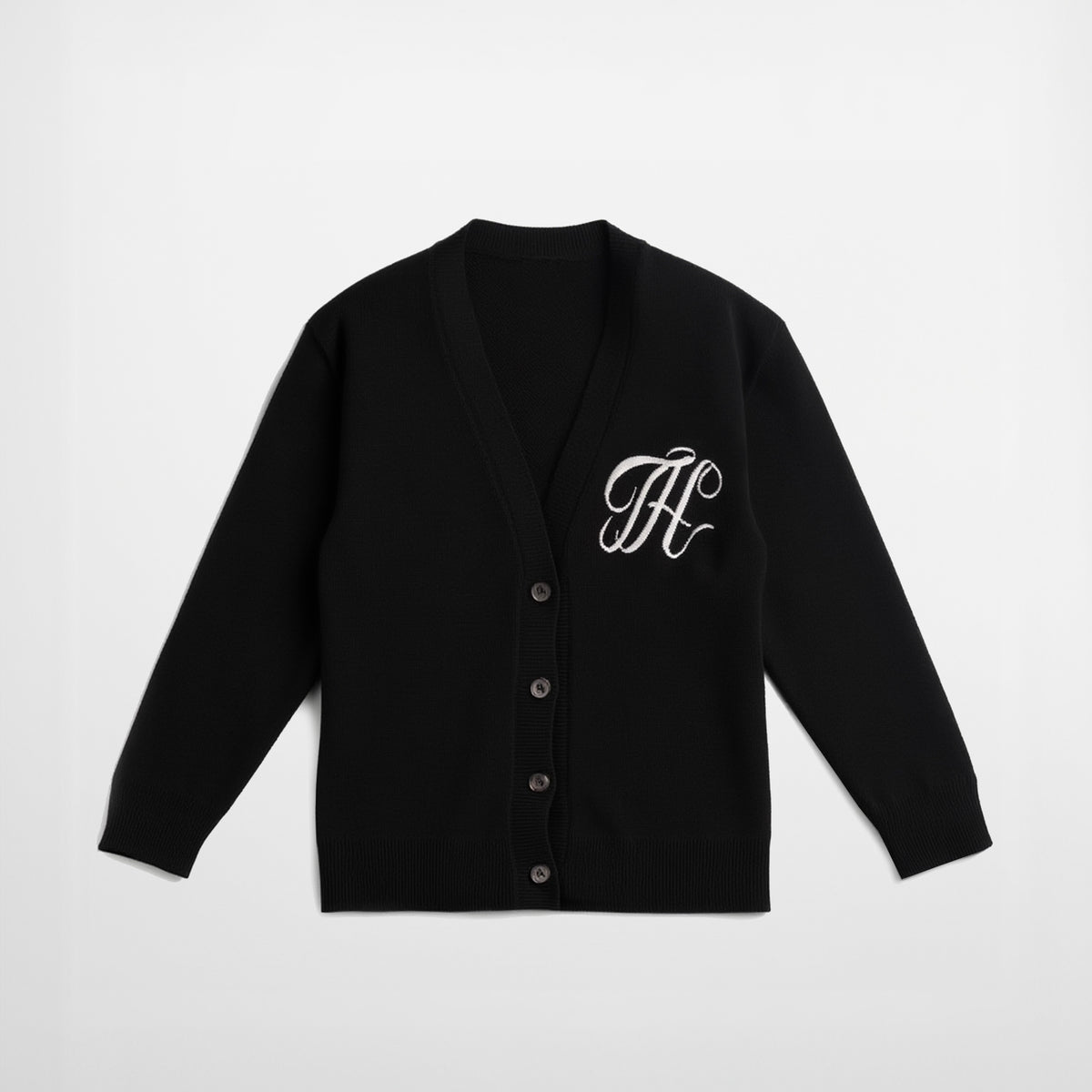 Black cardigan with white monogram on a light gray background